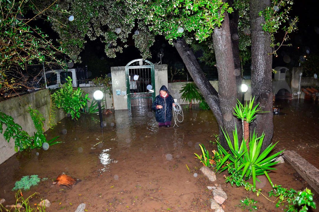 Eine Frau watet durch ihren gefluteten Garten.