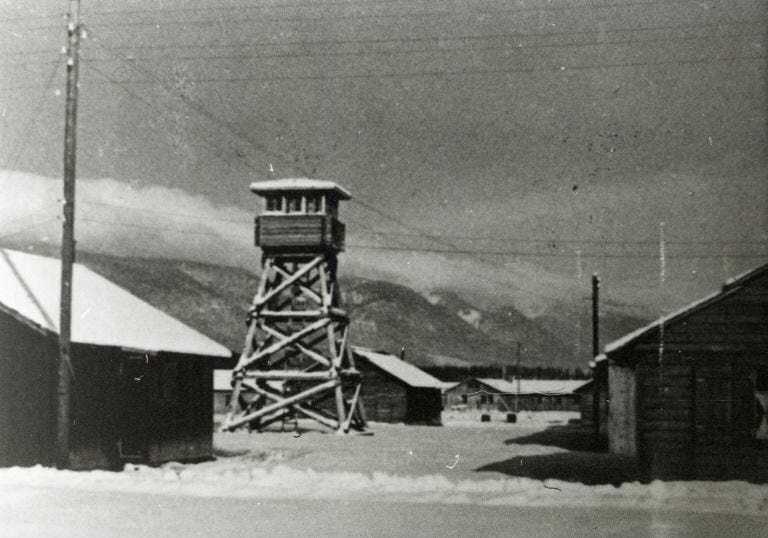 Wachturm und Baracken des Interniertenlagers, im Hintergrund der Jura, 1940
