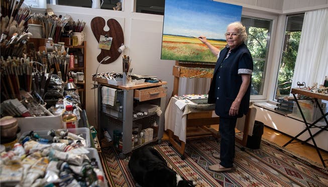 Die Künstlerin Kathy Thys in ihrem Atelier mit den vielen Pinseln, zusammen mit ihrer Hündin Luna. ZVG