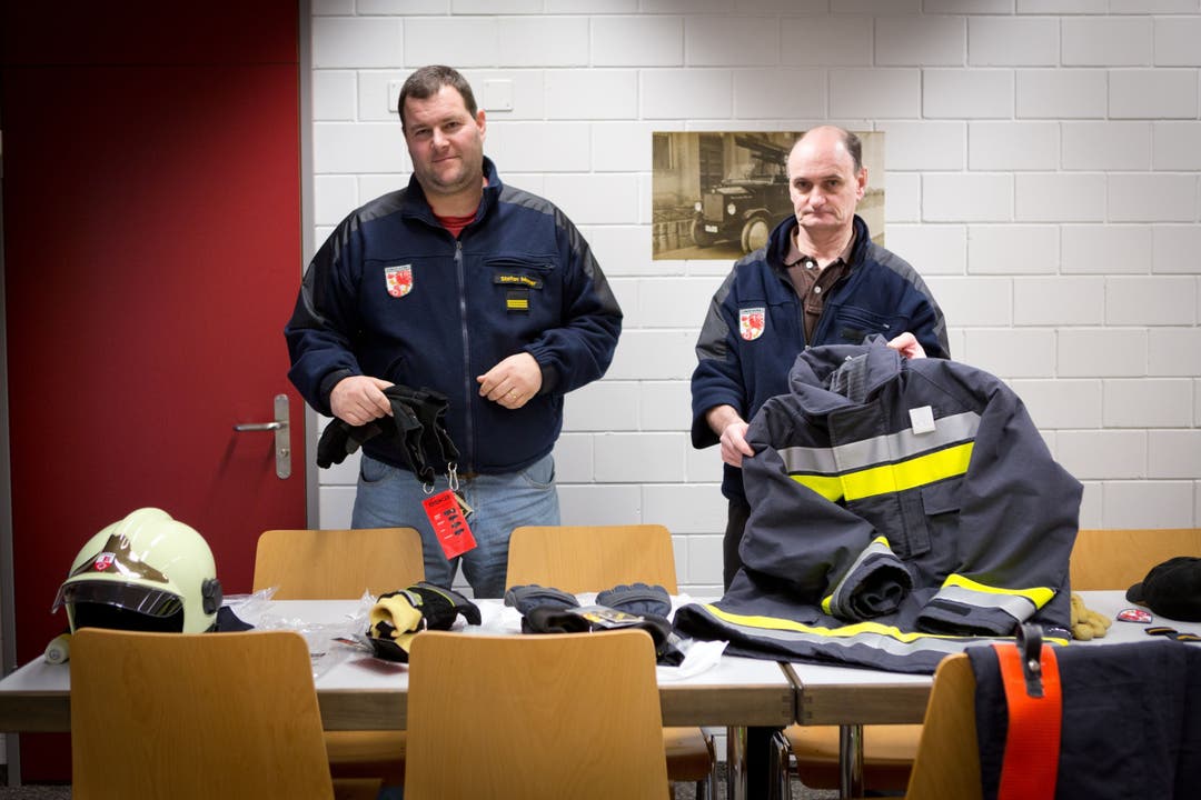 Feuerwehrkommandant Stefan Moser links und Materialwart Urs Hediger präsentieren Uniformteile