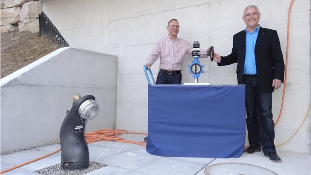 Gemeindeammann Willy Schürch (rechts) und Gemeinderat Roland Oeschger öffnen den symbolischen Schieber beim neuen Wasserreservoir in Münchwilen (links der Saughydrant für die Feuerwehr). – Foto: chr