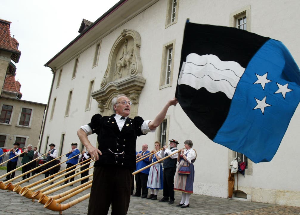 Ein Fahnenschwinger schwingt vor der Kaserne Aarau unterstützt von Alphornbläsern stolz die Aargauerfahne
