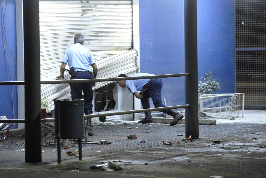 Zwei Polizisten inspizieren einen geplünderten Laden.