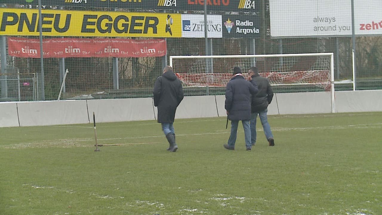 Sportchef Urs Bachmann, Schiedsrichter Martin Salm und der Platzwart des FC Aarau untersuchen das Terrain.