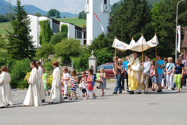 Ministrantinnen und Ministranten sowie Blumen streuende Kinder gehen in Aedermannsdorf dem Priester mit der Monstranz unter dem Baldachin voraus.