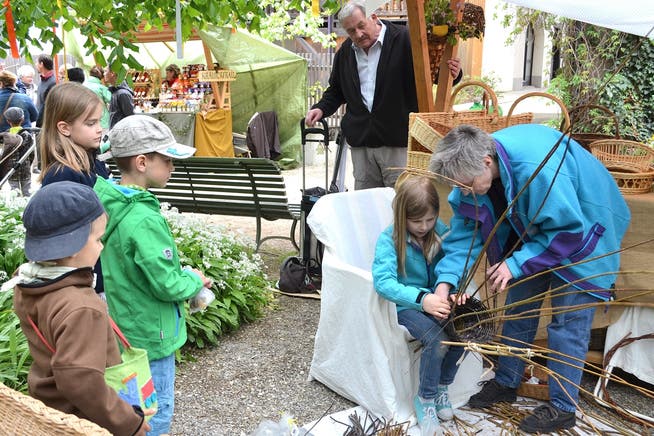 Eine junge Mühlifescht-Besucherin wird in die Kunst des Korbflechtens eingeweiht.