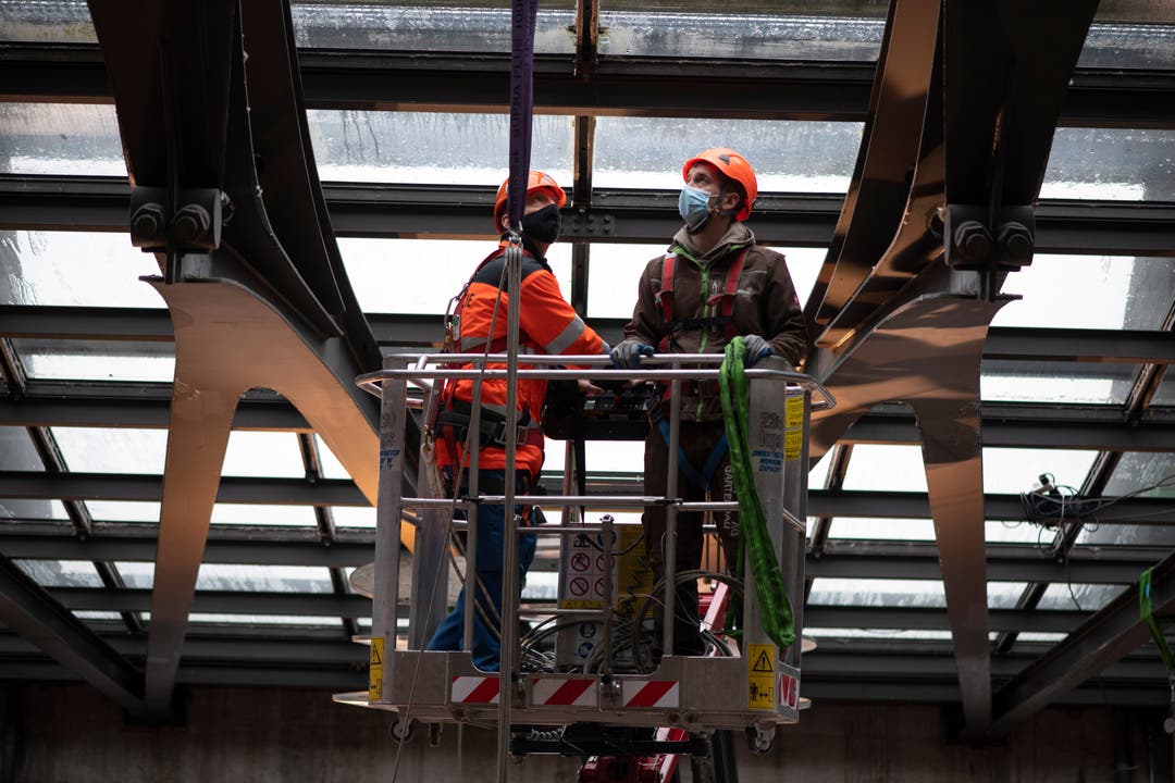 Spezialisten am Donnerstag beim Befestigen eines Sujets in der Luzerner Bahnhof-Eingangshalle.