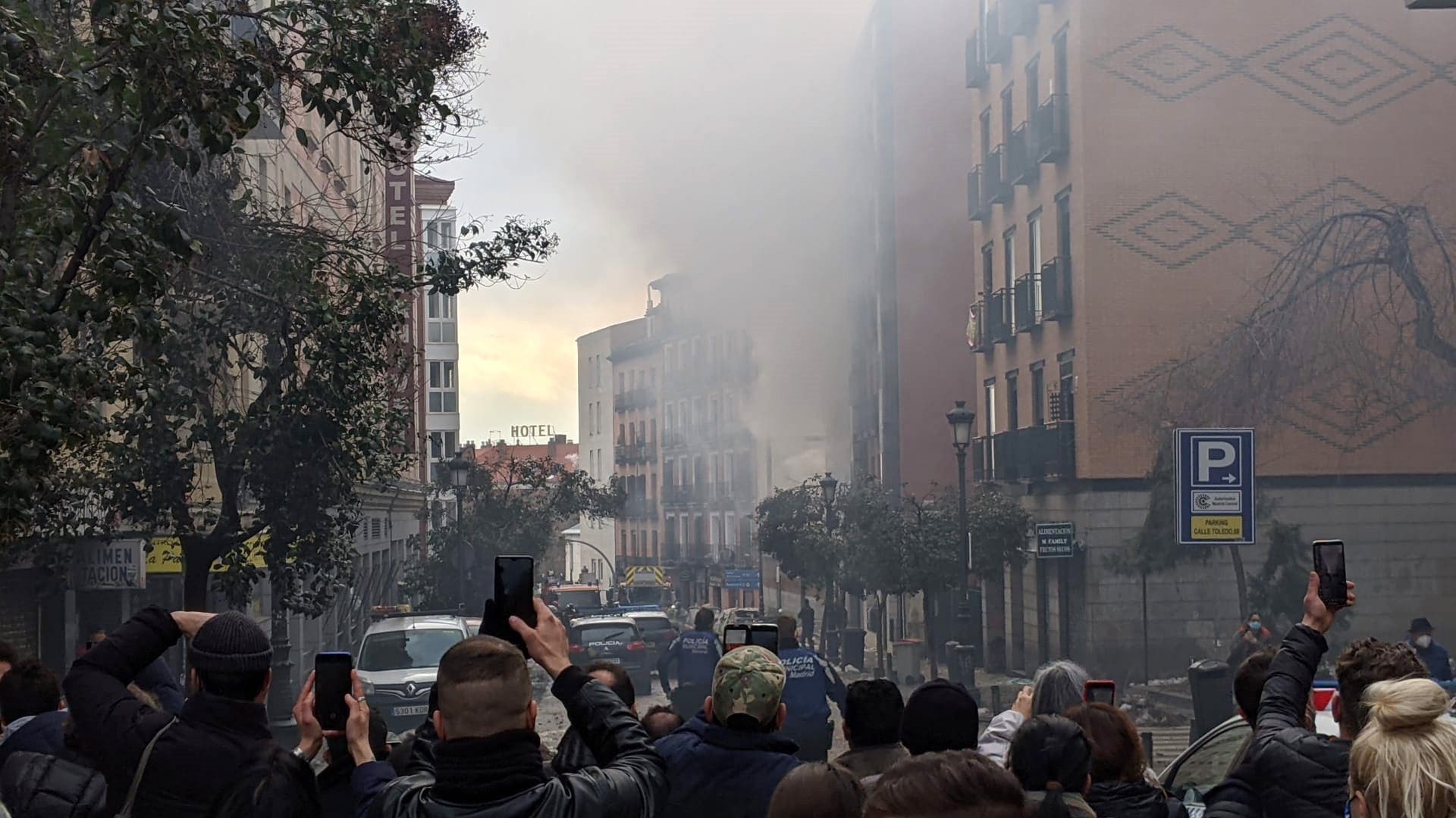Rauch und Staub in Madrid. Passanten filmen den Vorgang mit ihren Handys.