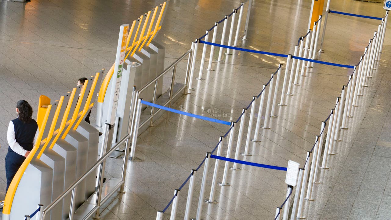 Ausgestorbene Flughäfen: Eine Mitarbeiterin des Frankfurter Flughafens steht neben dem leeren Wartebereich für die Gepäckabgabe.
