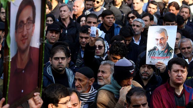 Teilnehmer an einer Beerdigung von sechs Abschuss-Opfern halten das Bild des ETH-Doktoranden Amir Ashrafi (links) in die Luft. Gleich daneben wird dem hohen Militär Qasem Soleimani gedacht. (Bild: Abbas Poustin Douz/Mehr Newsagency)