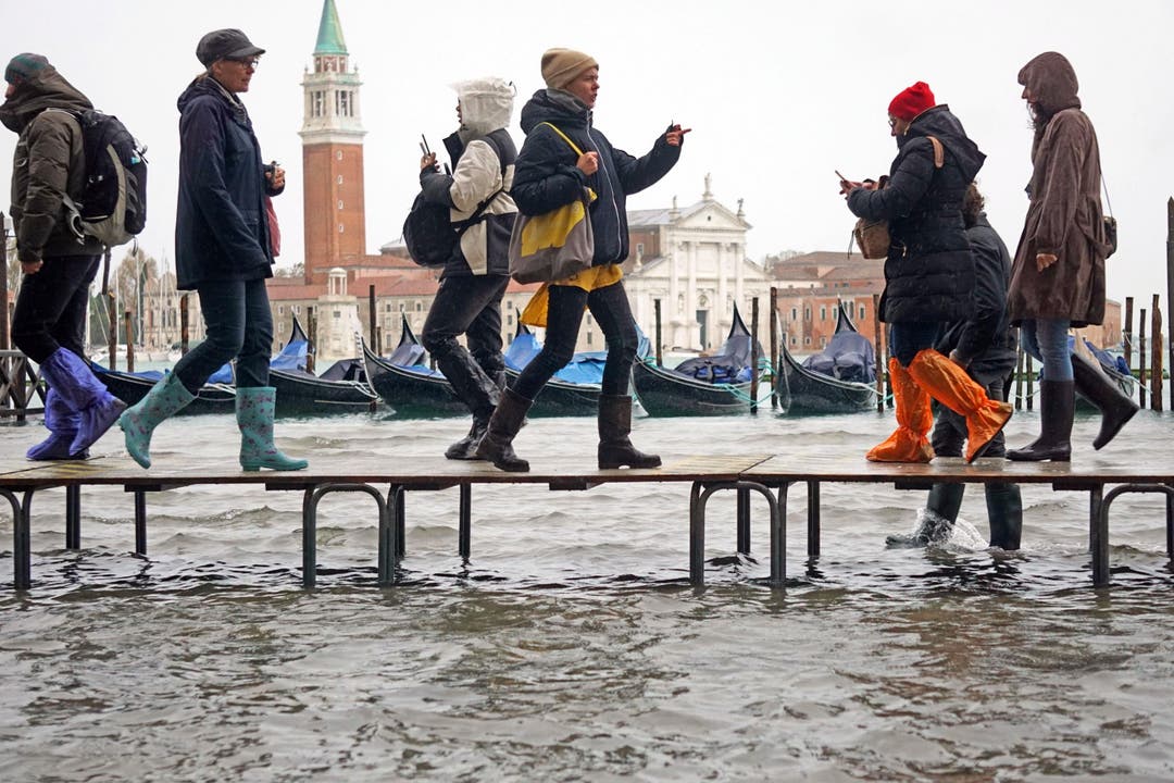 Menschen laufen auf Stegen in Venedig.