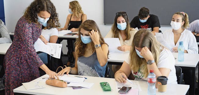 Kampf gegen das Coronavirus: Lehrerin und die Gymnasiasten tragen Maske.