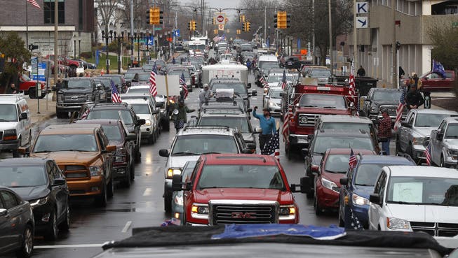 Proteste wie dieser in Lansing in Michigan gab es diese Woche in verschiedenen Städten der USA. Mit den Autos zu den jeweiligen Regierungsgebäuden fahren, Stau Flaggen schwenken, hupen – so demonstrieren US-Bürger.