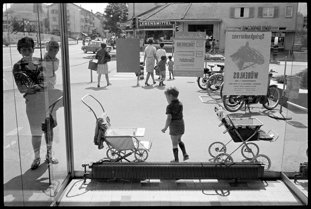 Familien beim Samstagseinkauf an der Landstrasse in Wettingen. Fotografiert durch Schaufenster, 1968.