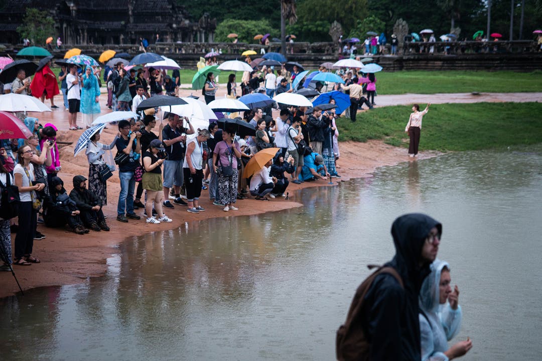 Bereits am frühen Morgen und bei Regen warten viele Touristen vor dem bekannten Tempel Angkor Wat.