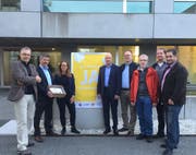 Die Übergabe der Unterschriften, das «Ja zum Einwohnerrat»-Plakat hängt auch schon (von links): Erwin Rast (SP), Sandor Horvath (GLP), Gemeindeschreiber-Substitutin Barbara Getzmann, Gemeindeschreiber Roland Baggenstos, Patrick Gunz (CVP), Peter Noser (Grüne), René Friedrich (FDP) und Stefan Bühler (SVP). (Bild: hor, Ebikon 27. September 2019)