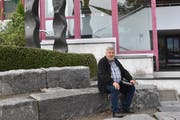 Der 66-jährige Josef Rütsche sitzt vor dem Schulhaus Neudorf in der «Arena», dem Aussenklassenzimmer. Dass dieses erhalten bleibt, war den Bürgern ein wichtiges Anliegen. Auch die Treppe im Hintergrund, die den Pausenplatz mit dem oberen Parkplatz verbindet, besteht weiter. (Bild: Timon Kobelt)