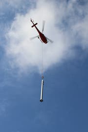 Immer wieder fliegt der Helikopter die rund 700 Kilogramm schweren Fahrleitungsmasten an den Ort, an dem sie platziert werden. (Bild: Martin Knoepfel)
