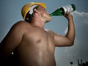 Ein Bauarbeiter erfrischt sich mit kühlem Wasser. (Bild Pius Amrein)