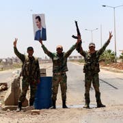Syrische Soldaten halten ein Portrait von Diktator Assad in die Höhe. (Bild: Youssef Badawi/EPA, Daraa, 7. Juli 2018)