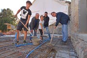 Fabian, Antonio, Rania, Andreas und Michael Mente verbuddeln die Zeitkapsel vor dem Betonieren im Boden. (Bild: Mario Testa)