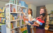 Désirée Stucki räumt Bücher aus dem Regal, Katharina Alder steht bereits mit den ersten Spielwaren bereit. (Bild: Mario Testa)
