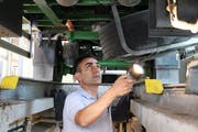 Mit einer Lampe kontrolliert Sandro Torre den Unterbau eines Lastwagens in der Prüfstelle Oberbüren. (Bild: Dinah Hauser)
