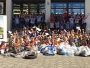 Sogar ein rostiges Velo und einen alten Pneu förderten die Hüttwiler Schulkinder zu Tag. Stolz posierten sie mit dem im Dorf eingesammelten Abfall. (Bild: PD)