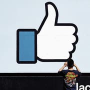 Ein Mann macht ein Foto des Like-Daumens von Facebook vor dem Hauptsitz des Unternehmens in Kalifornien nahe San Francisco. Bild: Marcio Jose Sanchez/AP (Menlo Park, 28. März 2018)
