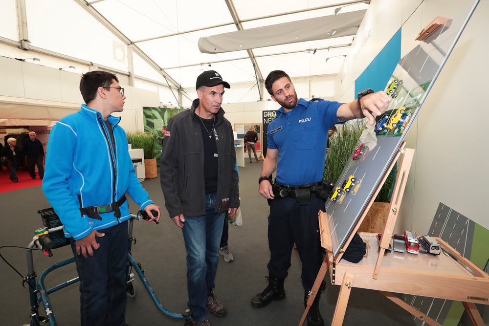 Rainer Henggele mit Sohn Jonas stellen dem Polizisten Marcel Müller am Stand der Zuger Polizei Fragen über den Verkehr. (Bild: Roger Zbinden (Zug, 20. Oktober 2018))