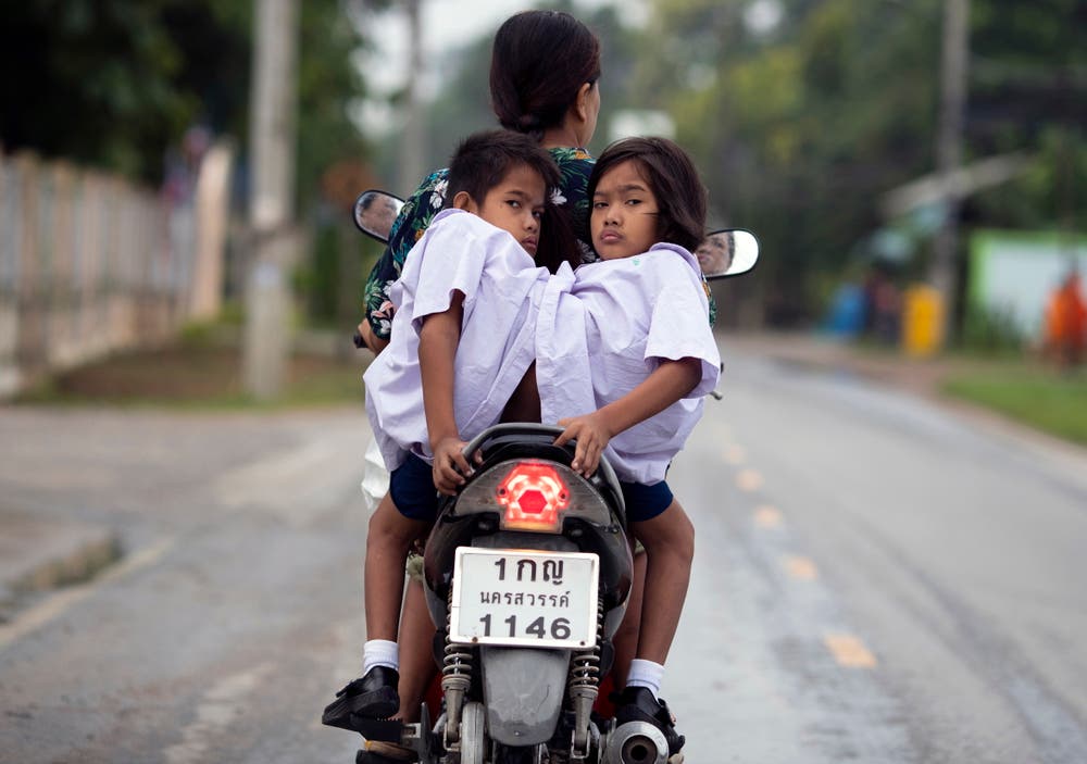 Die thailändischen Zwillinge Pan und Pin Romphoyen, die an der Hüfte zusammengewachsen sind, werden von ihrer Mutter in die Schule gefahren. (Bild: Rungroj Yongrit (Nakhon Sawan, 21. August 2018))