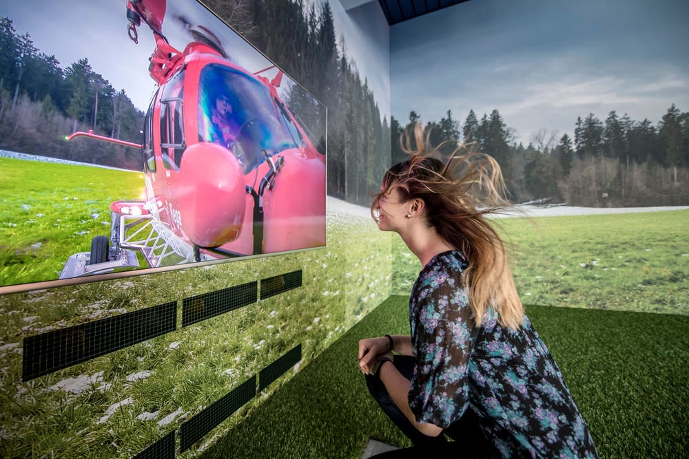 Ausstellung zur Rega im Verkehrshaus. Auf dem Bild zu sehen ist eine Besucherin, welche den «Abwind-Simulator» eines Helikopters bei der Landung testet. Bild: Pius Amrein (Luzern, 27. April 2018)