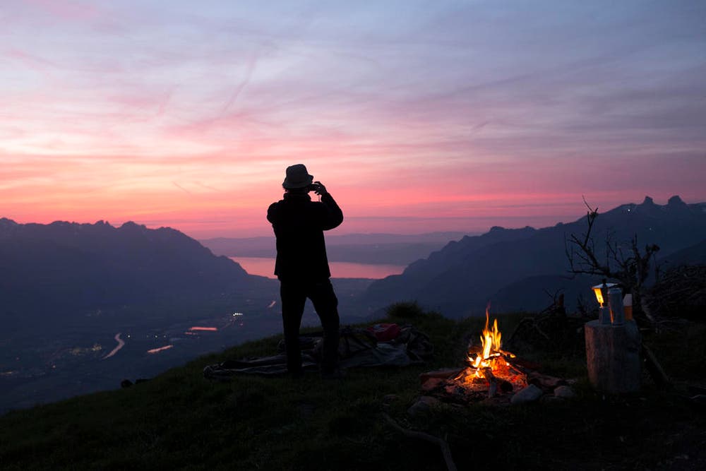 Ein Berggänger fotografiert den Sonnenuntergang in Bex / VD, im Hintergrund die Rhône-Ebene und der Genfersee. (Bild: Keystone / Anthony Anex)