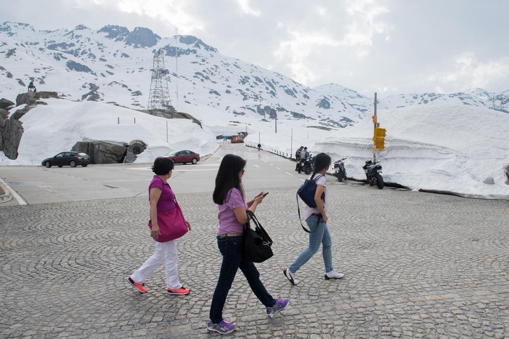 Die ersten Touristen spazieren neben den Schneemassen auf dem am 13. Mai eröffneten Gotthardpass. (Bild: DAVIDE AGOSTA)