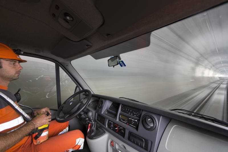Ein Lokführer sitzt in einem Minibus auf einem Transportzug und bedient den Zug per Fernbedienung (Bild: Keystone)