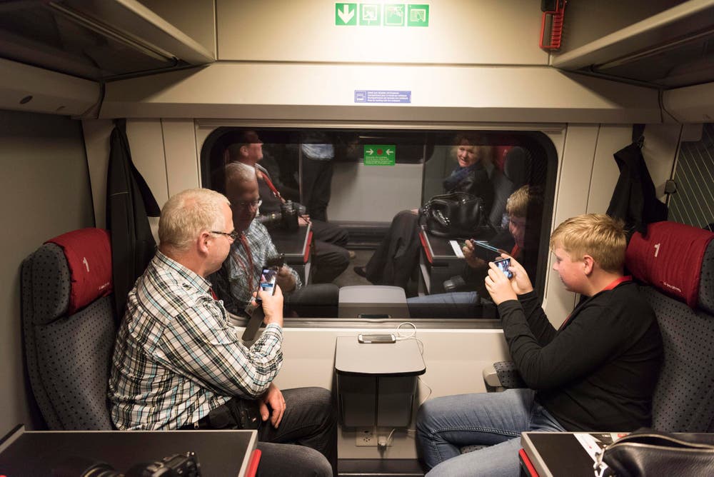 Zwei Premiere-Passagiere sehen nichts durchs Fenster. Da bleibt Zeit für Grüsse aus dem Tunnel. (Bild: Keystone / Epa / Christian Beutler)