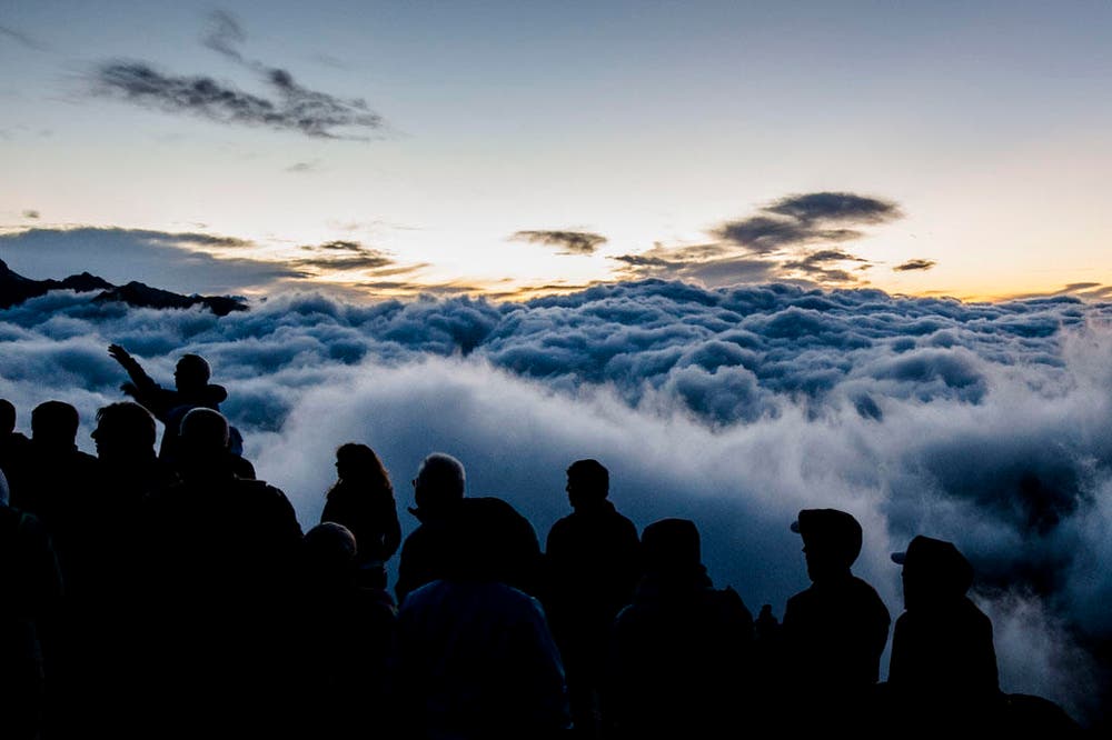 Touristen beobachten den Sonnenaufgang über dem Nebelmeer am Eggishorn. (Bild: Keystone / Dominic Steinmann)