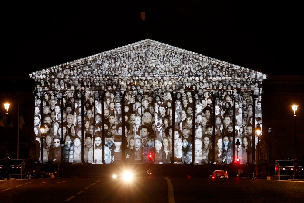 Der französische Künstler JR und der US-amerikanische Filmemacher Darren Aronofsky lassen Gesichter am französischen Parlamentsgebäude erstrahlen. (Bild: EPA / Yoan Valat)