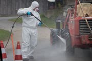 Ein Zivilschützer im Schutzanzug putzt eine Maschine, die in die «verseuchte» Zone fährt. Bild: Boris Bürgisser (Ruswil, 19. Oktober 2018)