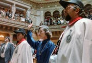 Vereidigung der ersten Frau zur Bundesrätin: In Begleitung von zwei Weibeln hebt Elisabeth Kopp am 2. Oktober 1984 in Bern bei ihrer Vereidigung im Nationalratssaal die rechte Hand zum Schwur. (KEYSTONE/Str)