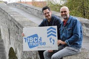 Die beiden Veranstalter, Lukas Zogg und Roland Geiger, präsentieren auf der alten Thurbrücke das Logo der Ausstellung. (Bild: Georg Stelzner)