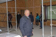 Erich Schaffer, Schulpräsident und Baukommissionspräsident, im neuen Mehrzweckraum. Im Hintergrund Interessierte. (Bild: Manuela Olgiati)