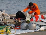 Indonesische Rettungskräfte untersuchen im Meer gefundene Wrackteile des Flugzeugs. (Bild: KEYSTONE/AP/TATAN SYUFLANA)
