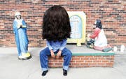 Apathische Figur mit übergrossem Kopf vor Hintergrund mit christlichen Figuren und den Zehn Geboten. (Bild: Nina Stähli aus «Glory Land»)