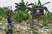 Eine nigerianische Frau an einem Schild, das vor verunreinigtem Land in der Gemeinde Ogale warnt. (Bild: Tife Owolabi/EPA (Nigerdelta, 9. März 2016))