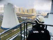 Ein Greenpeace-Mitglied schaut am Dienstag hinüber zum Schornstein des Kohlekraftwerks im südpolnischen Belchatow, den neun Aktivisten erklommen. (Bild: Keystone/AP)