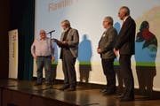 Nach der Bürgerversammlung wurde der Flawiler Preis verliehen. Hans Ruedi Fischer (am Mikrofon) hält eine Laudatio auf den Preisträger Heinz Niedermann (links), Gemeinderat Eddie Frei und Gemeindepräsident Elmar Metzger hören zu. (Bild: Tobias Söldi)