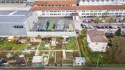 Blick auf das Firmenareal der DGS in St.Gallen-Winkeln: Wo heute noch Autos parkieren, werden künftig Bauteile für Elektrofahrzeuge gegossen. Für die Familiengärten im Vordergrund ist dann kein Platz mehr. (Bild: Urs Bucher)
