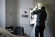 Ein Beamter der Kantonspolizei St. Gallen bei der Spurensicherung in einem Büro mit aufgebrochenem Safe. (Symbolbild: Urs Bucher)