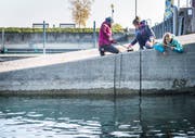 Drei Mädchen fischen Güsel aus dem See.